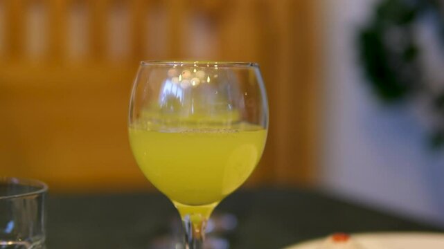 Pour orange juice Squeezing juice from half a tangerine to the glass by hand pressure, view on a background of other whole tangerines on a table