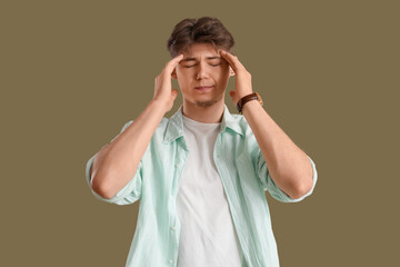 Portrait of young man suffering from headache on green background