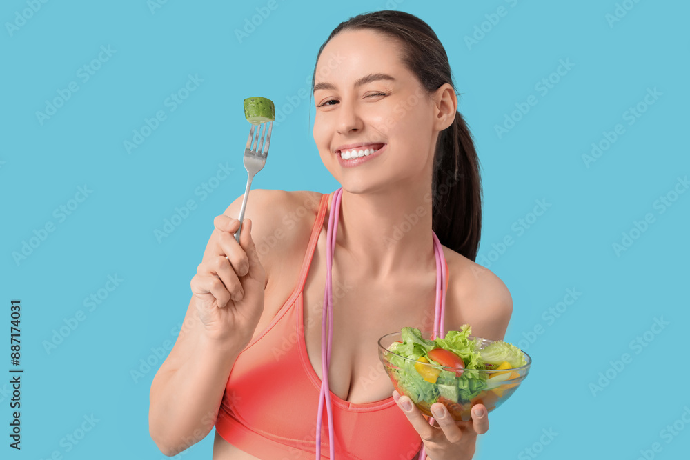 Poster beautiful young happy woman with jumping rope and bowl of fresh salad on blue background. weight los