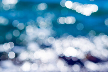 Sea waves rolling and crashing on the rocks with lots of white bokeh spots of sun glare on the...