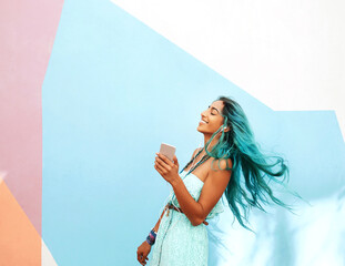Woman, movement and music at wall with smile, happiness and smartphone for streaming in summer. Hair, earphones and gen z girl with dance for freedom, expression or listening to favorite song