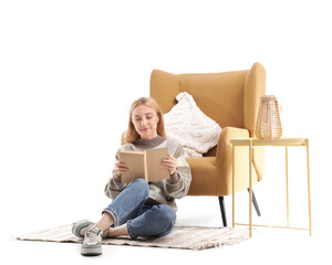 Mature woman reading book and sitting on floor near armchair isolated on white background