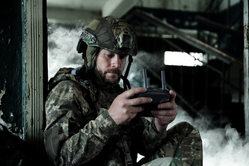 Fototapeta premium Soldier with drone controller inside building during military operation
