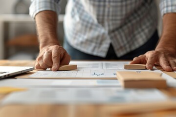 Close-up of a man in a plaid shirt analyzing charts and graphs spread out on a desk, representing data analysis and business planning.