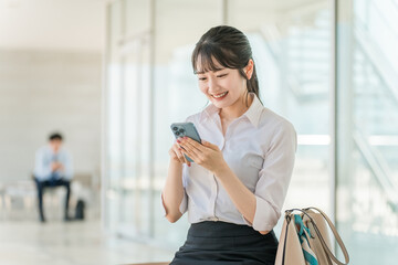 オフィスビルでスマホを使う若いアジア人ビジネスウーマン
