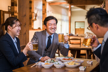 居酒屋で忘年会・新年会・飲み会・宴会をする仕事仲間・同僚・上司部下の男女
