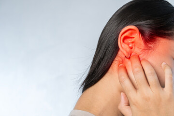 Young woman suffering from ear pain and tinnitus. Cause of earache includes otitis, earwax buildup.