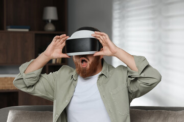 Emotional man using virtual reality headset on sofa at home