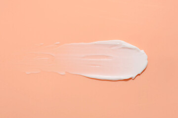 Sample of face cream on coral background, top view