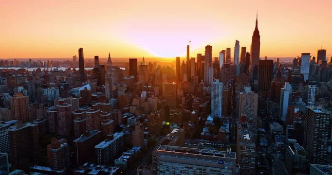 Golden light of setting sun lights the architecture of modern New York. Aerial perspective on beautiful metropolis at sunset.