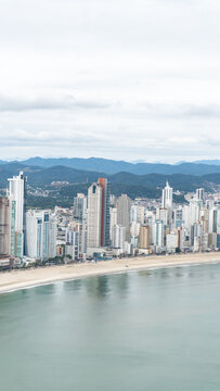 beachfront in Balne&aacute;rio Cambori&uacute;, Santa Catarina, Brazil, seen from above, beach and large building in the background.