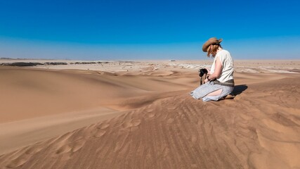 Lone woman traveling in a desert with sand dunes and a clear blue sky in Namibia, Africa