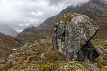 Large glacial erratic rock on the Routeburn Track, Fiordland National Park, New Zealand. The Route Burn river is on the valley floor in the background.
