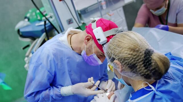Treating thyroid eye disease by means of surgical intervention. Male surgeon uses metal tools in his work. Top view.
