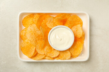 Potato chips in a bowl with sauce on a light background
