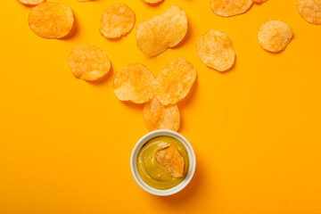 Potato chips with mustard on a yellow background
