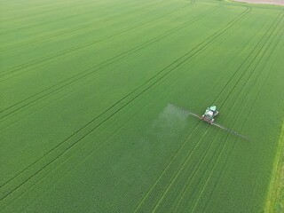 Tractor spraying a phytosanitary product on a huge green field - Tracteur qui &eacute;pand un produit phytosanitaire sur un immense champ vert