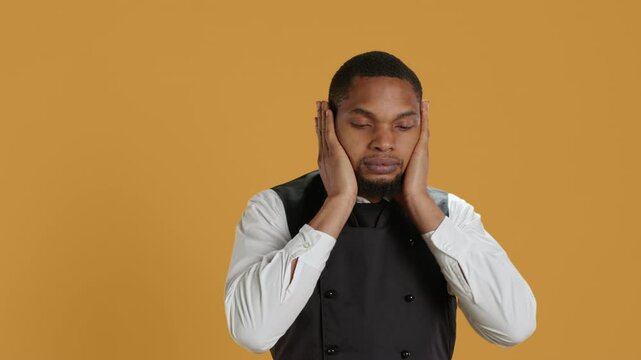 Restaurant staff covering his eyes, mouth and ears against evil in studio, presenting three wise monkeys metaphor. Waiter doesnt see, hear or speak as a concept, hospitality industry. Camera A.