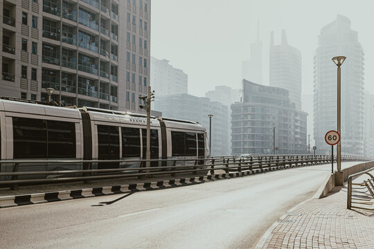 Modern tram crossing a bridge in Dubai with high-rise buildings on the background