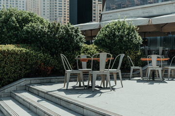 Outdoor cafe seating with metal chairs and wooden tables on a sunny day