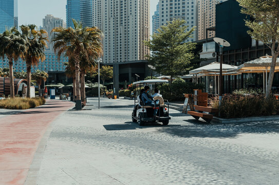 Golf cart driving through urban park with high-rise buildings on the background