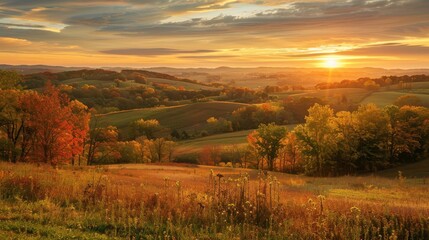 Fototapeta premium A vibrant sunrise paints the sky in shades of orange and yellow, illuminating rolling hills covered in autumn foliage. Trees with leaves in various shades of red, orange, and yellow stand in the foreg