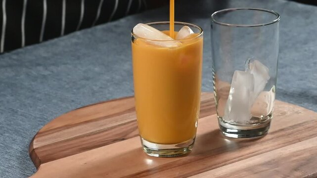 Indian food  Mango lassi or smoothie also called as milk shake pouring into  a glass from blender. 