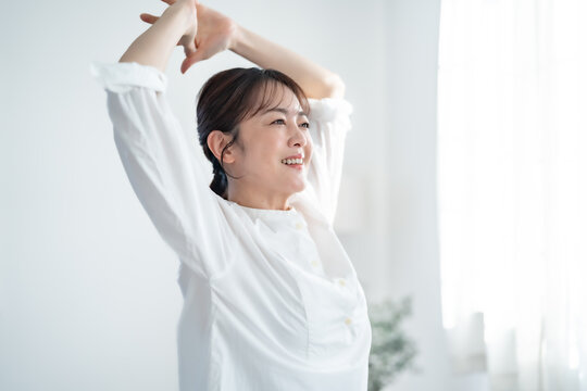 部屋で伸びをする女性