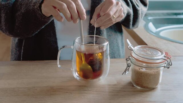 Stirring Tea With a Spoon in a Double-Walled Mug on a Wooden Table