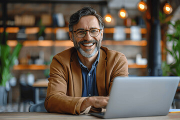 Obraz premium Smiling Businessman Having Fun During Online Video Call on Laptop at Desk in Office