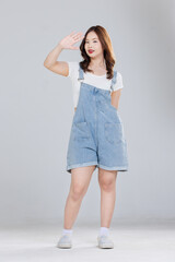 Portrait of Asian cute cheerful young girl wearing denim overalls, stylish model woman with happy and cool sweet smile standing posing isolated on white background, Teenage and youth fashion.
