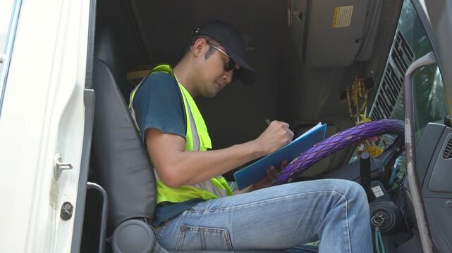 Asian Male truck driver signing documents.