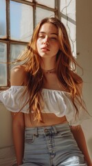 Fototapeta premium A woman with long brown hair is wearing a white top and blue jeans