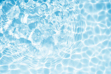 Blue water with ripples on the surface. Defocus blurred transparent blue colored clear calm water surface texture with splashes and bubbles. Water waves with shining pattern texture background.