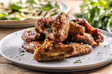 Grilled chicken wings on a plate and grilled zucchini as a side dish