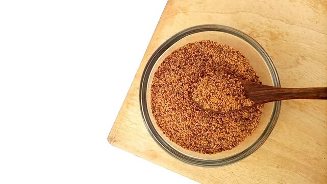Taking Fenugreek seeds from the glass bowl with a wooden spoon, top view, herbs and spices.