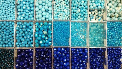 Set of luxury sorted blue beads of different sizes of blue shade in cells. Storage and sale of blue beads for needlework, closeup, top view.