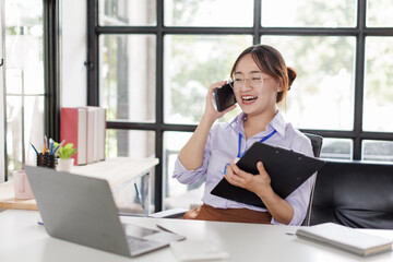 Happy asian business woman call centre representative customer support agent talking to client, smiling asian female working using laptop computer in office.