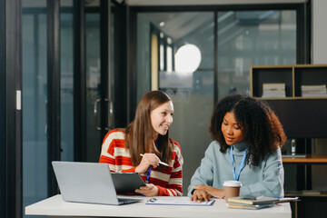 Two business workers talking on the smartphone and using laptop