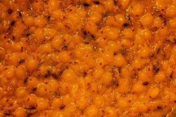 Close-up of sea buckthorn jam: bright orange sea buckthorn berries in thick syrup, shiny texture
