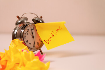 Deadline: Close-up of an alarm clock and sticky notes, emphasizing the urgency