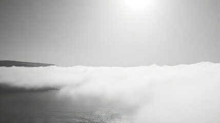Fototapeta premium A monochrome image of a vast expanse of water shrouded in mist, with a mountain fading into the haze in the background