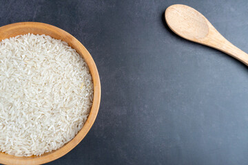 half of wooden bowl filled rice with spoon on stone table