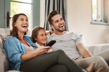 Parents, girl and watching tv on couch with laugh, remote and relax together for bonding in family house. Father, mother and child with connection, happy and streaming with film, cartoon or movies