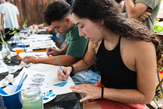Group of friends participating in a charitable painting workshop during the summer