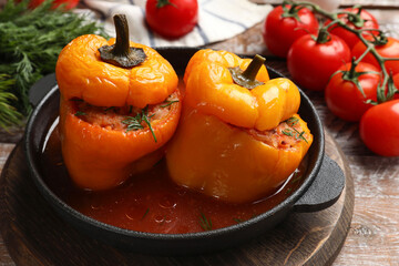 Tasty stuffed peppers in pan and products on wooden rustic table, closeup