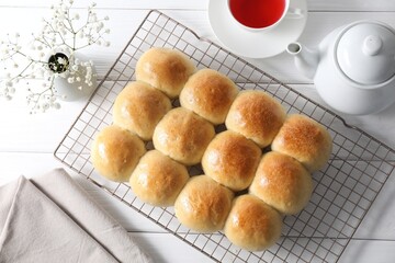 Delicious dough balls, tea, teapot and gypsophila flowers on white wooden table, top view