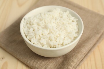 Delicious boiled rice in bowl on wooden table, closeup