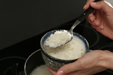 Woman taking boiled rice into bowl, closeup