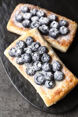 Tasty puff pastries with blueberries on grey table